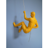 Yellow man climbing wall sculpture