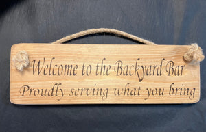Welcome to the backyard bar serving what you bring wooden roped sign